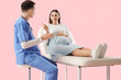 © Pixel-Shot - Young pregnant woman lying on couch with doctor against pink background