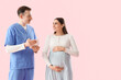 © Pixel-Shot - Young pregnant woman and doctor with tablet computer on pink background