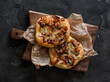 Vegetarian mini pizza with caramelized pear, blue cheese, honey and walnuts on a wooden chopping board on a dark background, top view