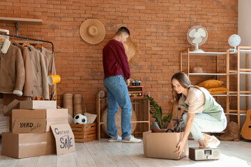 Canvas Print - Young couple packing in room of unwanted stuff