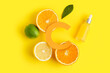 Paper letter C, bottle of essential oil and fresh citrus fruits on yellow background