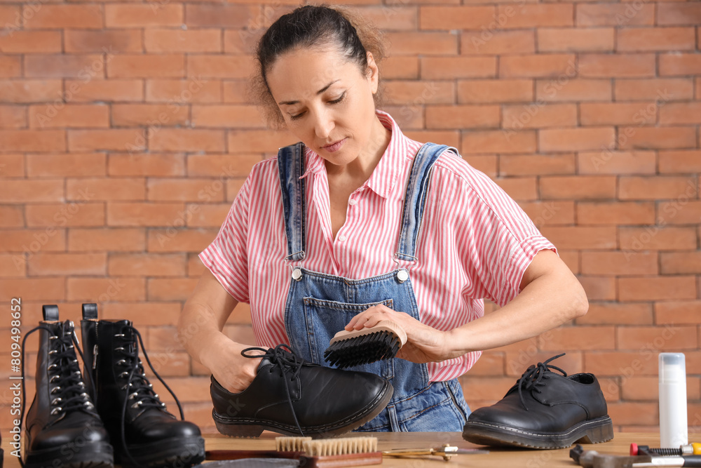 Female shoemaker polishing shoes in workshop
