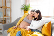 © Pixel-Shot - Young pregnant lesbian couple sitting on sofa at home