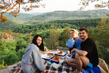 Fototapeta Miasto - happy friends eating pizza at the cliff with beautiful mountain view