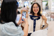 A woman taking a picture of her friend with a new clothe, having a fun shopping day together.
