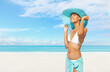 Happy young woman at the beach side, wearing a turquoise sun hat, bikini and pareo, portrait of African latin American woman in sunny summer day with blue sky, concept of a summer holiday