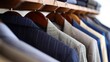 A row of clothes hanging on a rack, including a blue striped jacket. The clothes are neatly hung and organized, giving a sense of order and tidiness