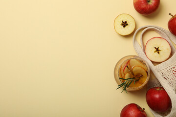 Wall Mural - Glass of apple cider and apples in bag on beige background, space for text