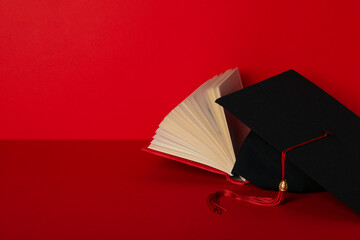 Wall Mural - Graduate hat and books, on a red background.