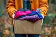 Volunteer hands holding a clothes donation box filled with clothing items