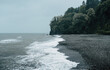 Misty beach view with gentle waves washing over pebbled shore under cloudy skies creates serene and tranquil seascape.