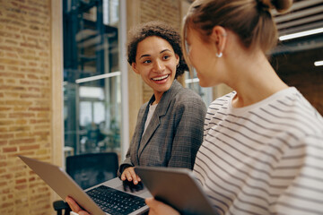 Wall Mural - Two businesswoman working together using laptop pc and talking about project