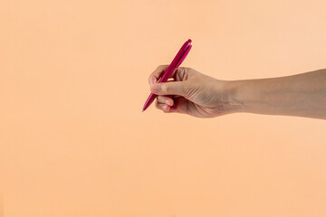 Wall Mural - Red plastic pen in hand. Isolated on cream background