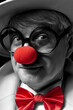 Close-up selective color portrait of a clown. An elderly man in a white coat and hat.