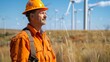 Engineer in safety gear observing wind turbines in a field
