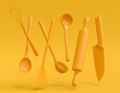 Wooden kitchen utensils, tools and equipment on yellow monochrome background.