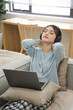 © Q88 - Portrait of Asian woman sitting on sofa at home