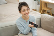 © Q88 - Portrait of Asian woman sitting on sofa at home