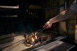 Male chef hand with kitchen tongs preparing woods in burning fire place