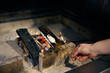 Cropped male chef hand frying marshmallow on tree branch in burning fire place