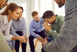 Group of people trying to support and encourage frustrated man. Team of supportive male and female colleagues, friends or group therapy members sitting in circle and comforting sad, upset young man