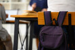 School backpack hanging on a wooden chair in classroom. Back to school concept