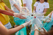 © Studio Romantic - Environmental problems. Variety of plastic containers are in hands of children who clean up garbage in park. Close up of children's hands in latex gloves holding plastic trash standing in circle.