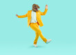 Energetic young man dancing wearing dinosaur head mask. Full size photo of freaky eccentric guy wearing stylish yellow suit having fun over isolated studio background