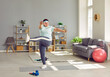 Full length photo of a happy funny young smiling fat overweight woman wearing sportswear doing fit exercise in the living room at home. Workout sport, fitness and body positive concept.