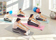 Group of young sporty girls, women stretching on mat, warming up with coach, fitness club sportswomen holding group exercise, happy team workout, improve flexibility. Active friends and sport together