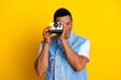 © deagreez - Photo of optimistic guy dressed jeans waistcoat holding retro camera on eye make photo isolated on vibrant yellow color background