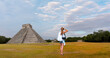 Young girl is standing and taking photos The pyramid of Kukulcan in the Mexican city of Chichen Itza in  the background - Mayan pyramids in Yucatan, Mexico