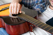 A young man plays the guitar at home. Close-up. Selective focus.