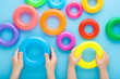 Little children hands holding colorful plastic rings on light blue table background. Pastel color. Toys of development for kids. Playing together. Point of view shot. Closeup. Top down view.
