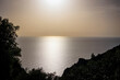 The sun sets golden over the sea against the silhouette of the coast at the ruins of Angelokastro near Agios Spiridon on the island of Corfu