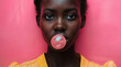 Young black girl blowing a bubble with bubble gum against a pink backdrop