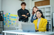 © Wasana - A woman in a yellow jacket is sitting at a desk with a laptop. She is smiling and she is working on something. The scene suggests a positive and productive atmosphere