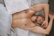 Muscular man and stretching arms in bed for rest, relax and sleep at home on weekend from above. Male person or model with strong body on pillow and blankets for comfort, peace and recovery portrait