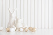 Easter rabbits figurines and eggs on white background. Easter celebration concept. Copy space. Front view