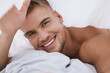 Wake up, portrait or happy man in bedroom with cover or pillow for resting in home, house or apartment. Smile, relax or lazy guy sleeping on break with peace, blanket or wellness on weekend chill