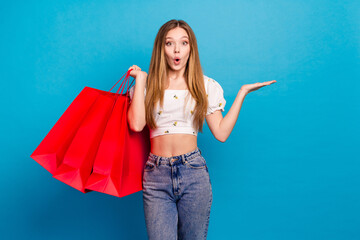 Poster - Photo of nice young girl arm hold empty space bags wear top isolated on blue color background