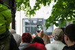 Man  photographing a street festival with camera phones. Young man taking photo of events using mobile phone . Rear view
