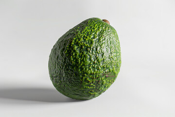 a green avocado on a white surface