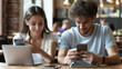 Close up view of man and woman using smartphones discussing mobile apps concept, couple talking holding cellphones synchronizing information online with laptop, checking news or texting messages.