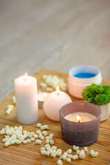 Closeup of a bright modern massage room interior details, burning candles and blue massage salt standing on a bamboo mat