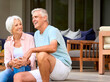 Loving Senior Couple Sitting Outdoors On Deck At Home Together