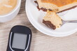 Glucometer for measuring and checking sugar level, piece of fresh baked sweet cheesecake and cup of coffee with milk