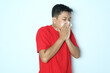 Young Asian man is suffering from flu and sneezing. Wearing a red shirt