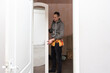 © Angelov - Young caucasian brunette man standing half sideways,holding with hands the middle door of a closet with a mirror to set,close up side view with selective focus. Furniture assembly concept.