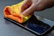 Detail of hand cleaning smartphone screen with microfiber cloth